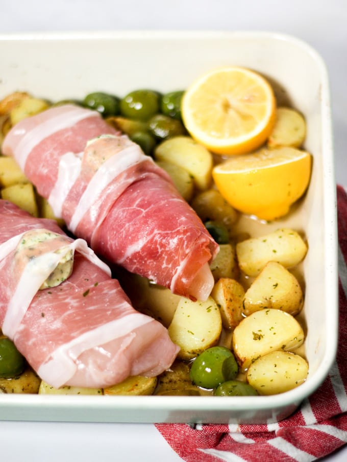 Chicken wrapped in bacon with potatoes, olives and lemon ready to be roasted