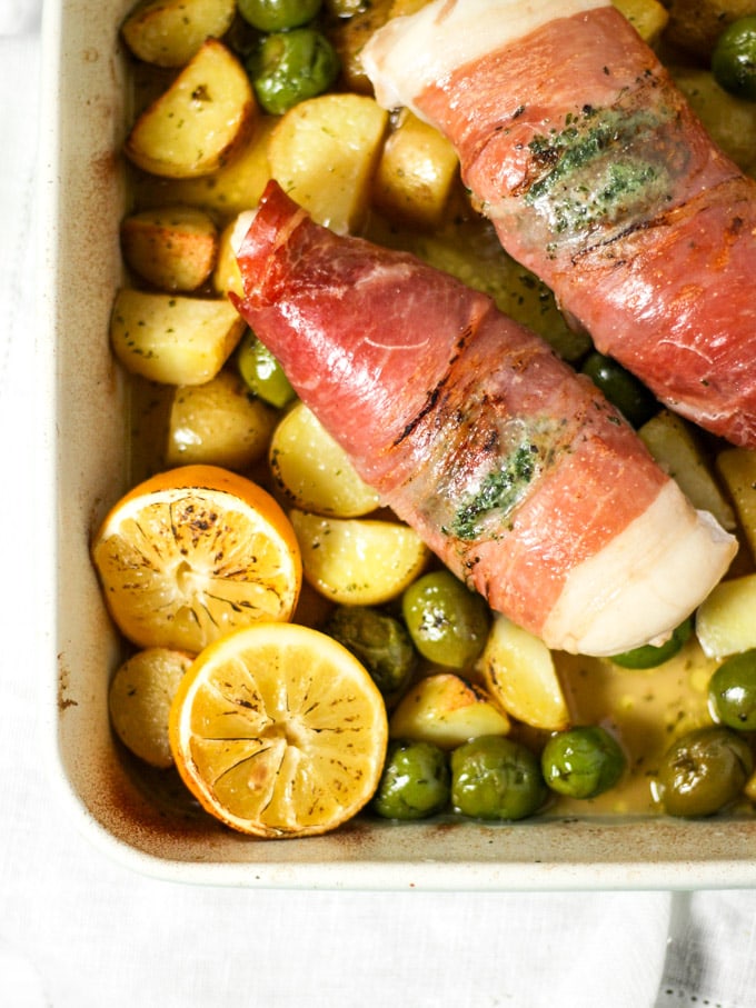 Chicken wrapped in bacon with roasted potatoes, lemons and olives