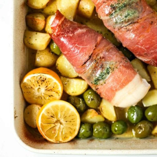 Chicken wrapped in bacon with potatoes, olives and lemon