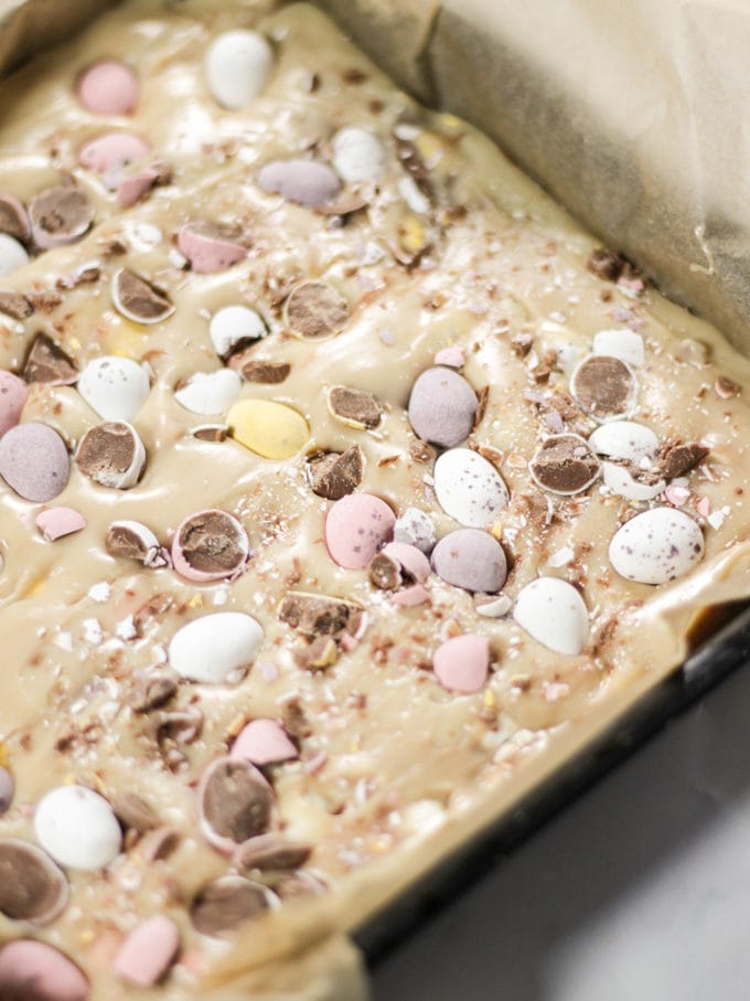 Mini Egg fudge mixture in a black metal tray before going into the fridge.