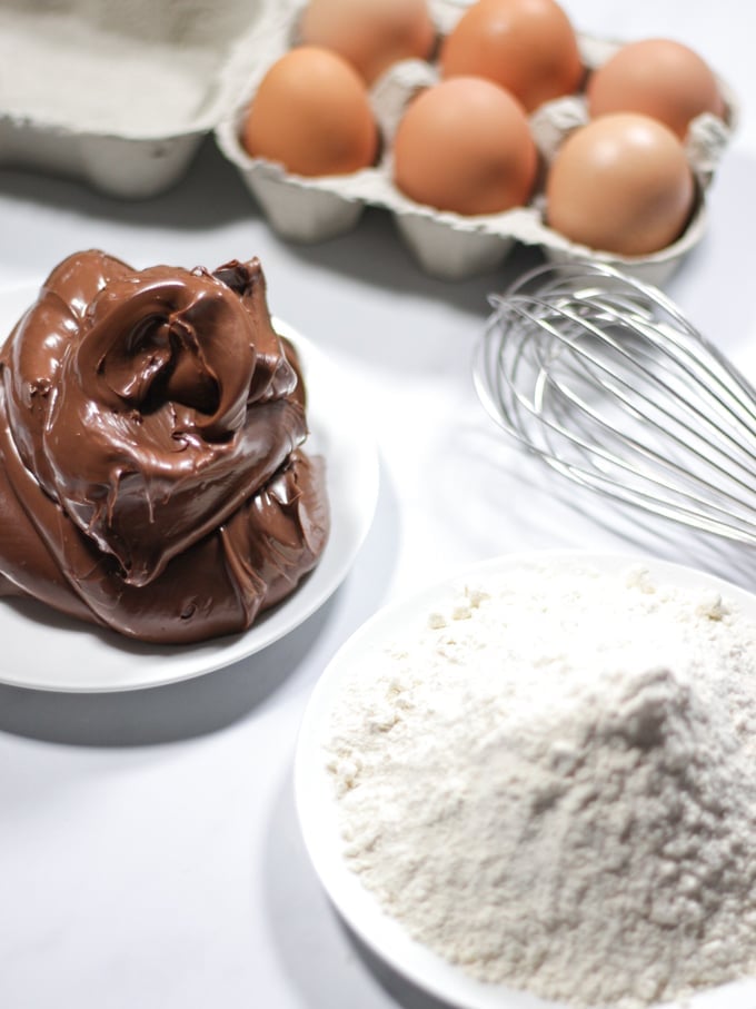 Nutella, eggs and flour plus whisk for 3 ingredient Nutella brownies recipe