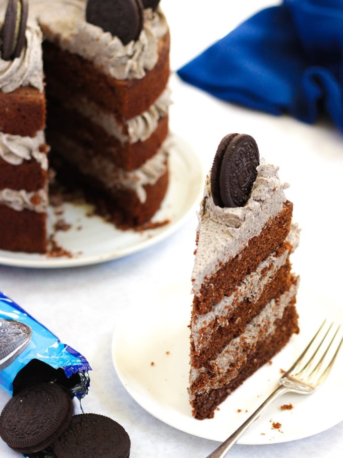 Slice of Oreo cake on a white plate with cake in the background