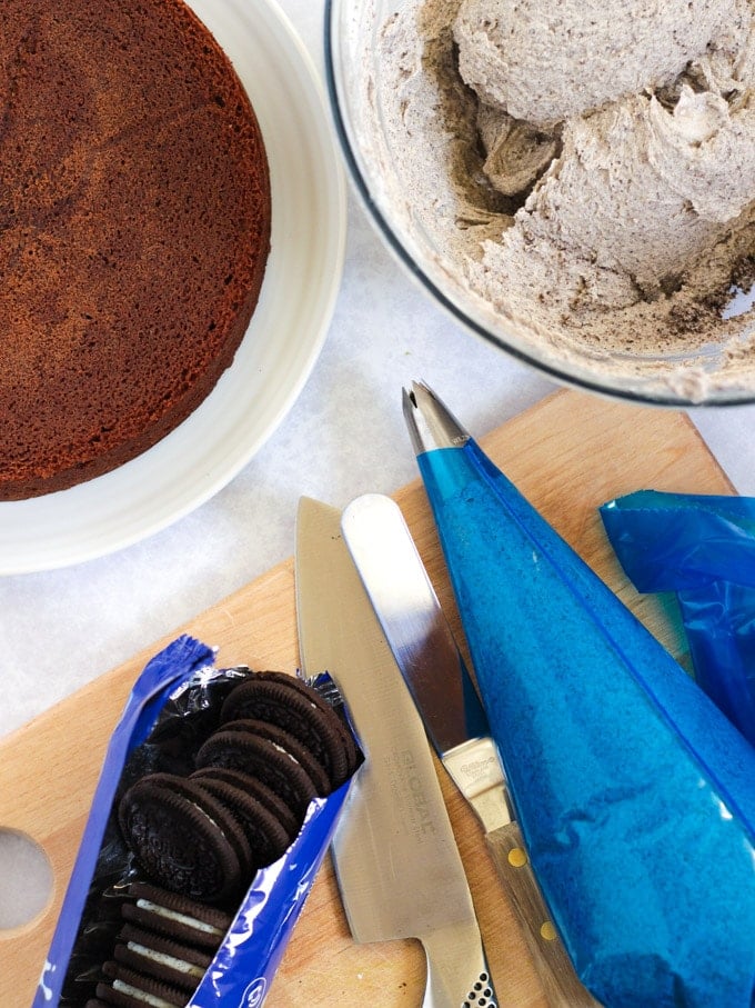 Oreo frosting in a piping bag and chocolate cake ready to decorate