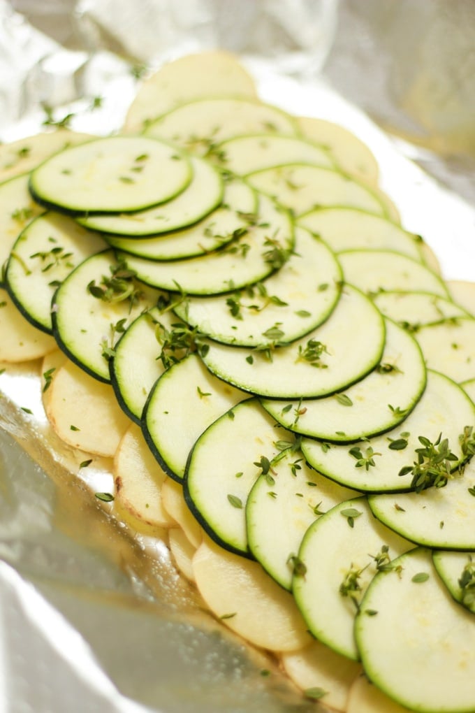 slices of raw potato and courgette layered on foil