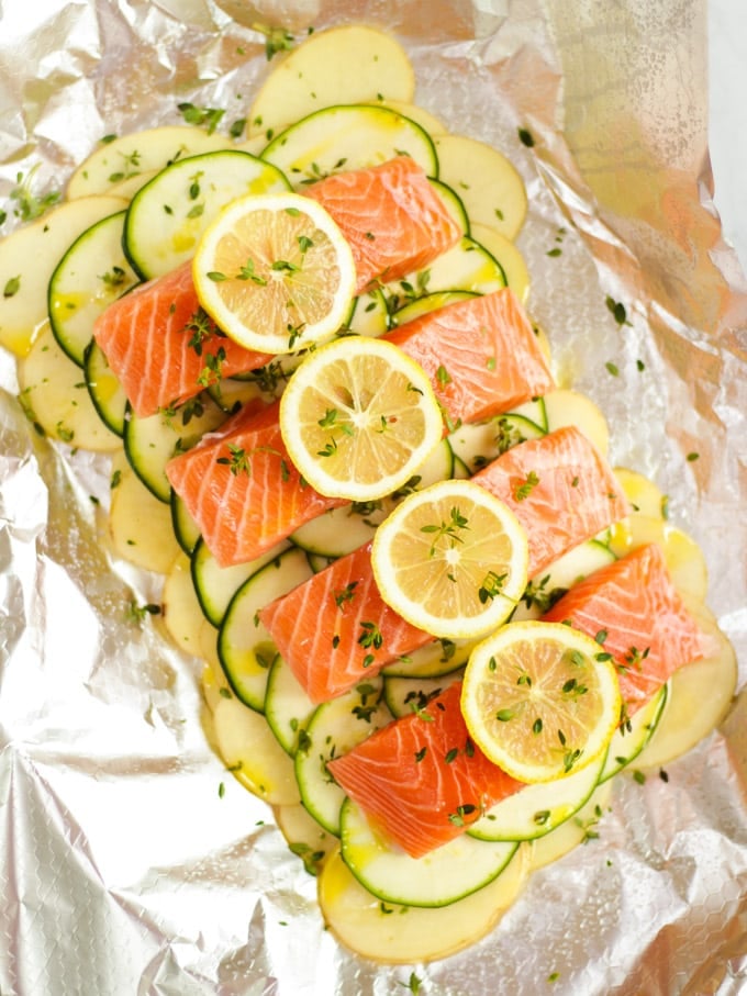 Fish fillets with lemon slices ready to be cooked on potatoes sliced and courgettes