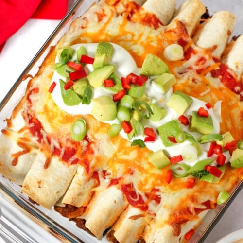 Beef enchiladas topped with sour cream, avocados, spring onions and chilli.