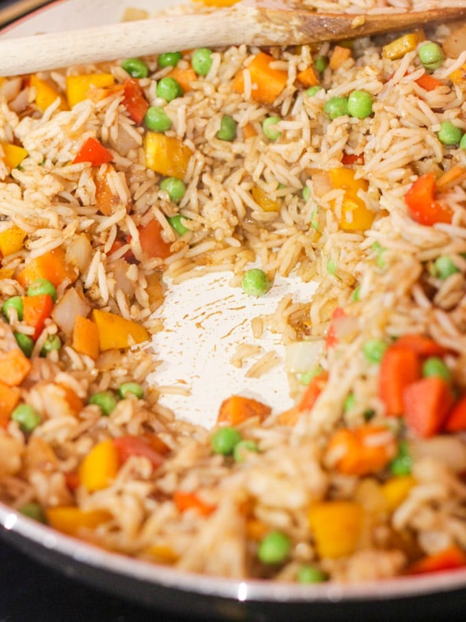 Fried rice in a pan with peas ready for egg to be added
