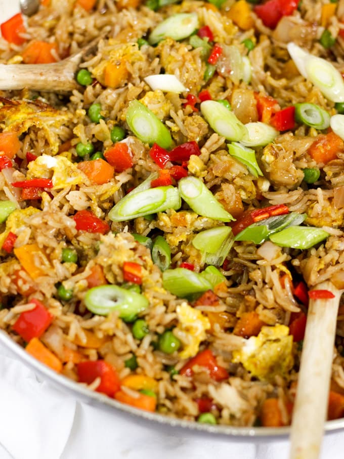 Egg fried rice in a frying pan with peas, peppers and spring onion.
