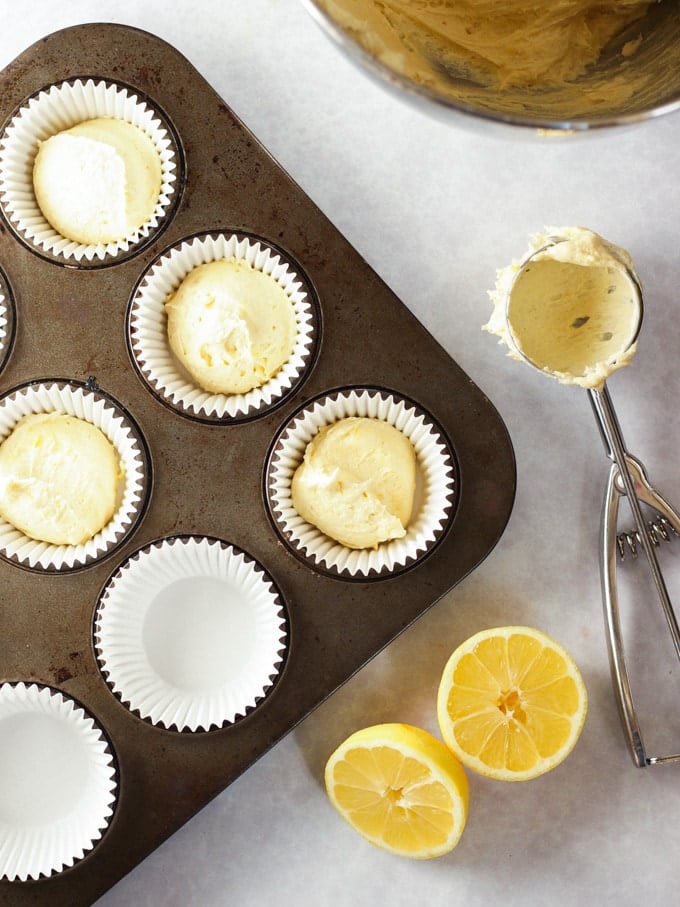 Cupcakes scooped into a muffin tin with a cupcake scoop ready to be baked