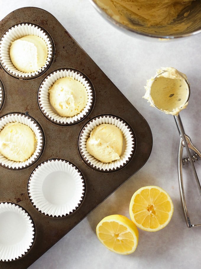 Cupcakes scooped into a muffin tin with a cupcake scoop ready to be baked.