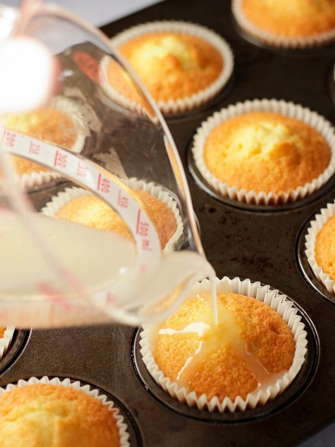 Baked cupcakes having lemon drizzle poured over them