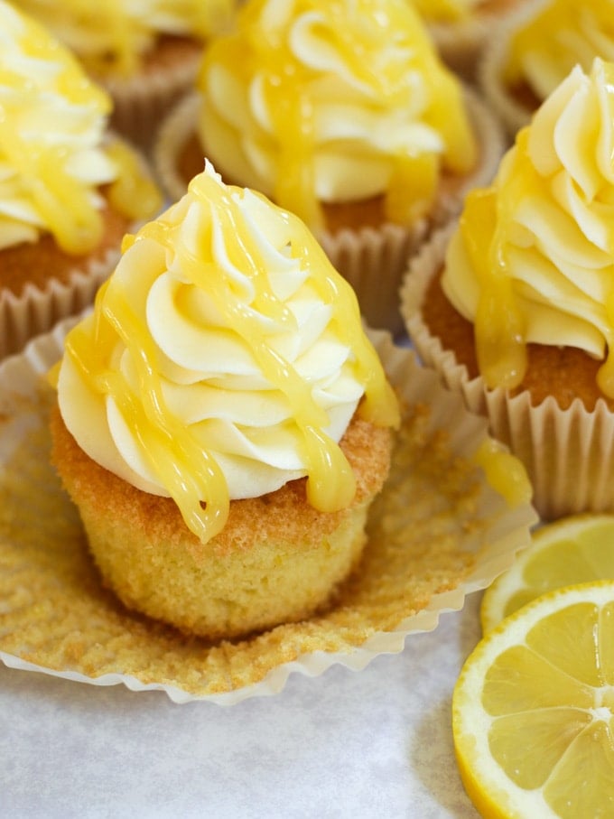 Lemon drizzle cupcake out of paper case with lemon curd and lemon frosting topping.
