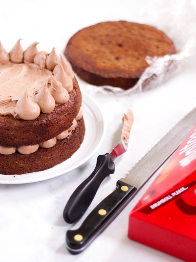 Chocolate cake being piped with malt icing