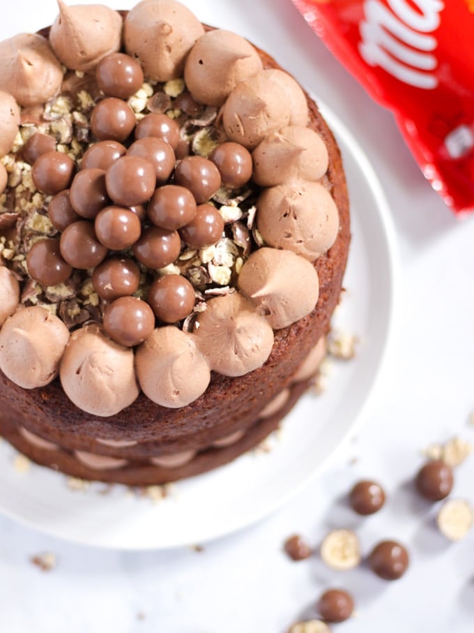 Malteser Cake on a white plated with bag of chocolates in background