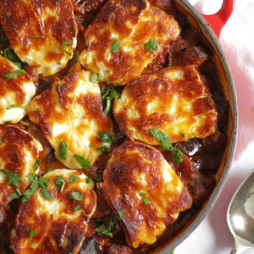 A pan filled with tomato vegetable sauce topped with golden halloumi cheese.