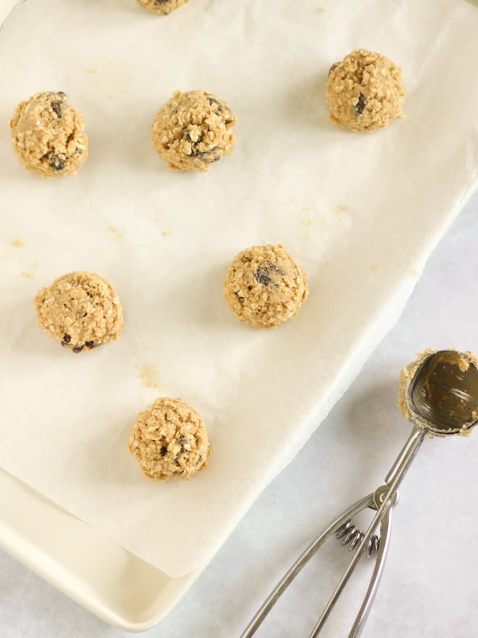 Scoops of cookie dough on a baking sheet with ice cream scoop