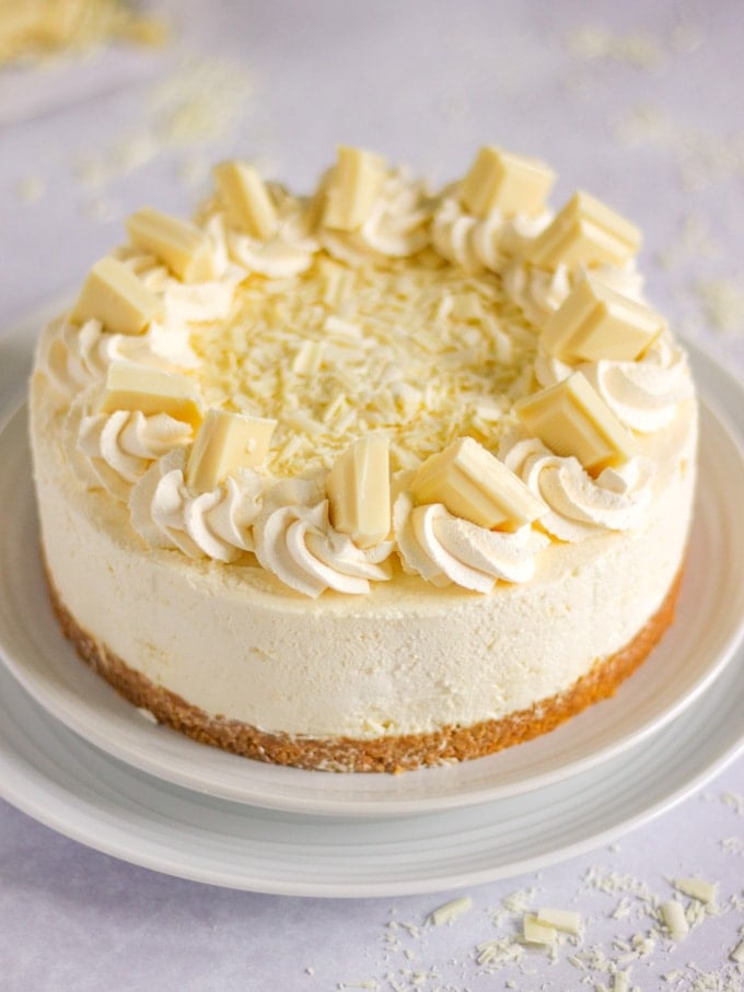 White chocolate cheesecake (no bake) with swirls of cream and chunks of white chocolate on top.