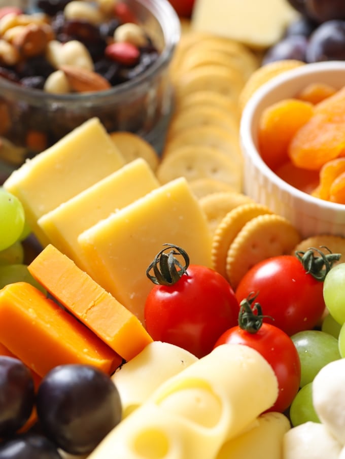 Cheese, tomatoes, grapes and crackers on a board