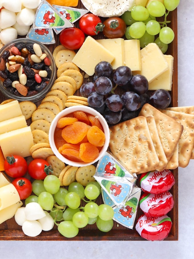 Apricots, grapes and cheeses with crackers on a board