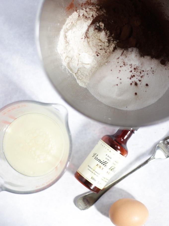 Bowl of flour, sugar and cocoa with a jug of egg, milk and oil