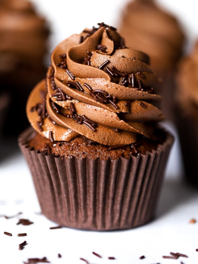 Moist chocolate cupcakes with milk chocolate icing and sprinkles.