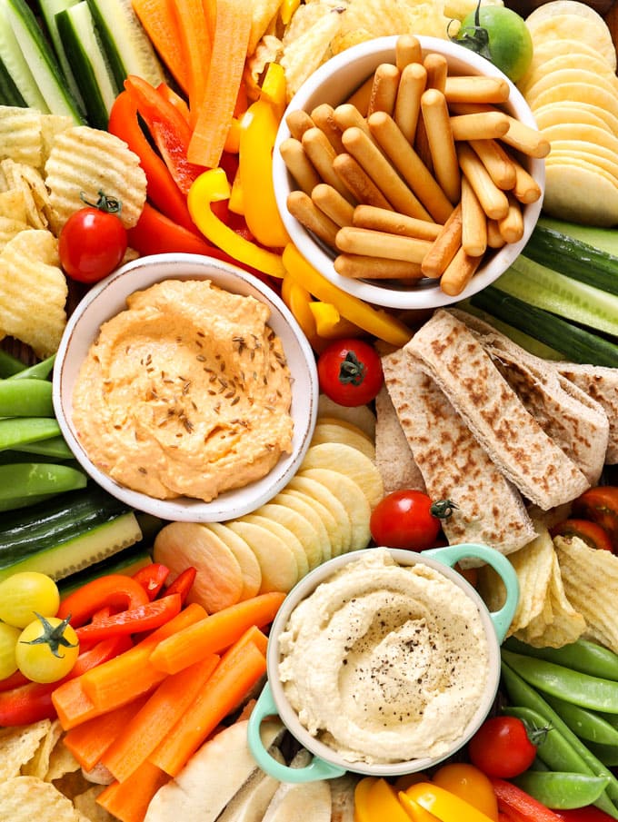 Hummus platter with breadsticks, dips, crisps, cucumber, tomatoes, carrots and crisps