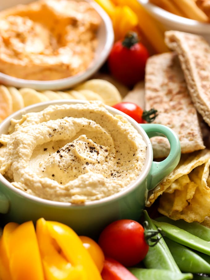 Close up of houmous with crisps and peppers and pitas