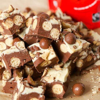 Microwave Malteser fudge in a pile of cubes with packet of chocolate in the background