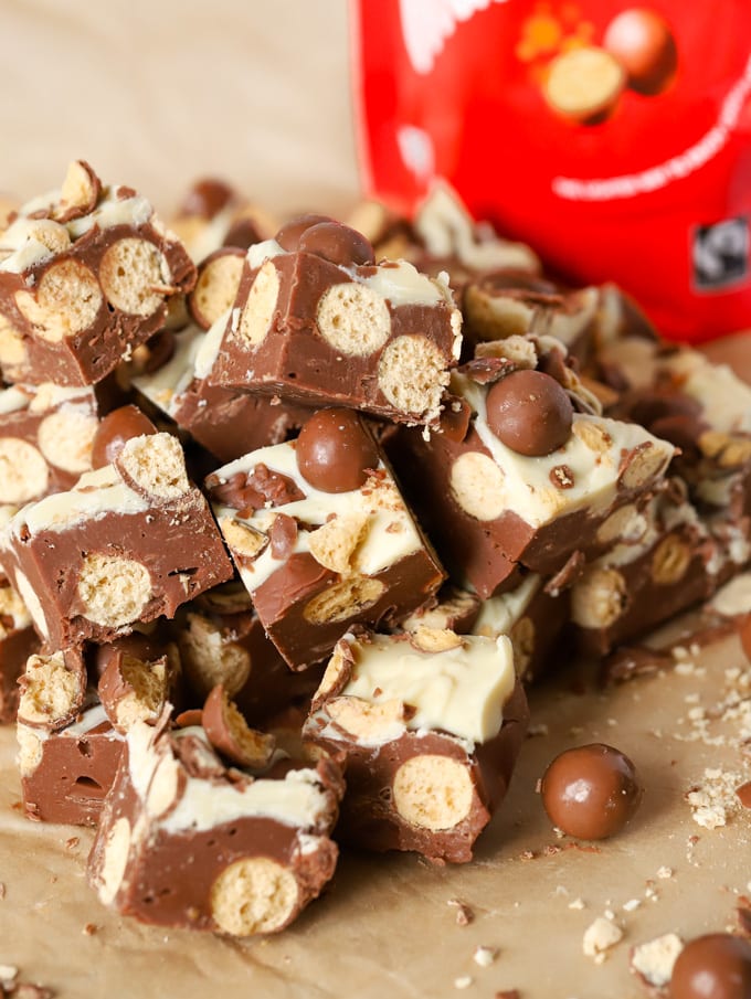 Microwave Malteser fudge in a pile of cubes with packet of chocolate in the background.