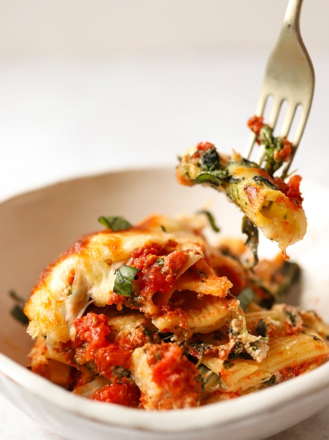 Bowl of spinach and ricotta pasta bake being eaten with a fork