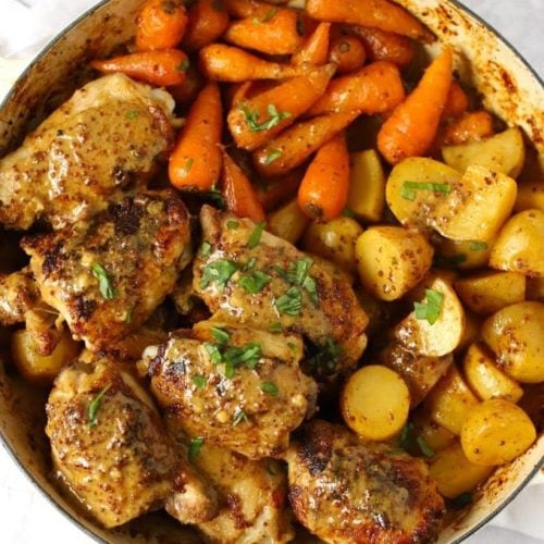 A large pan of chicken with carrots and potatoes to make up a tray bake of Honey Mustard Chicken recipe.