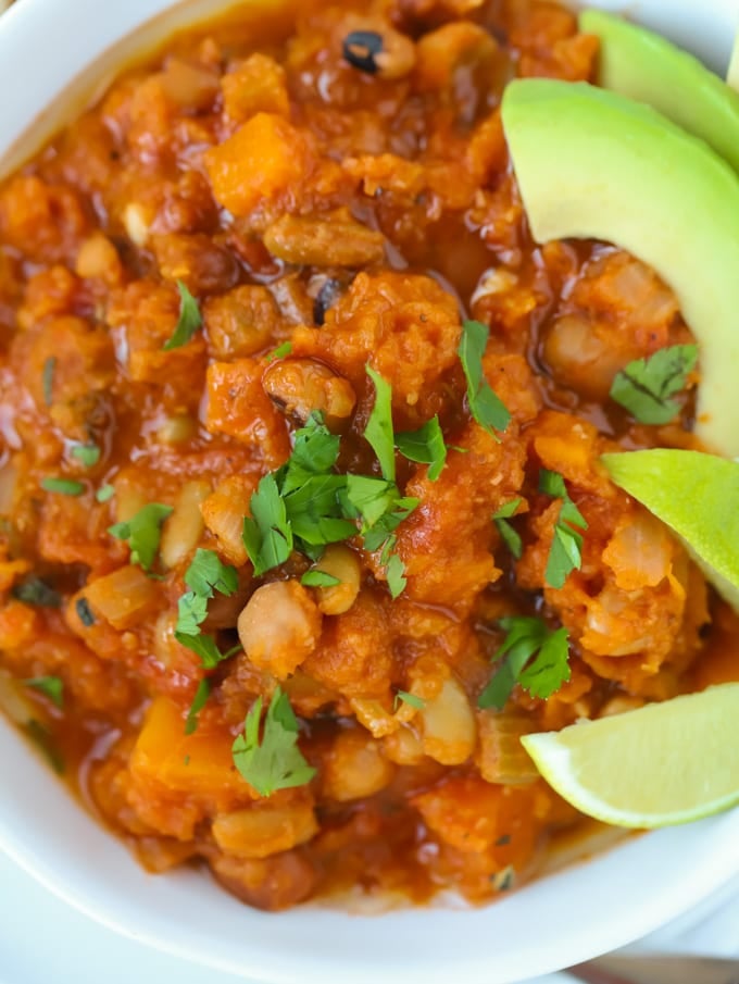 Vegan chilli in a bowl topped with herbs, avocado and lime