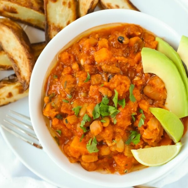 Vegetarian chilli recipe with butternut squash and chipotle served with potato wedges and avocado