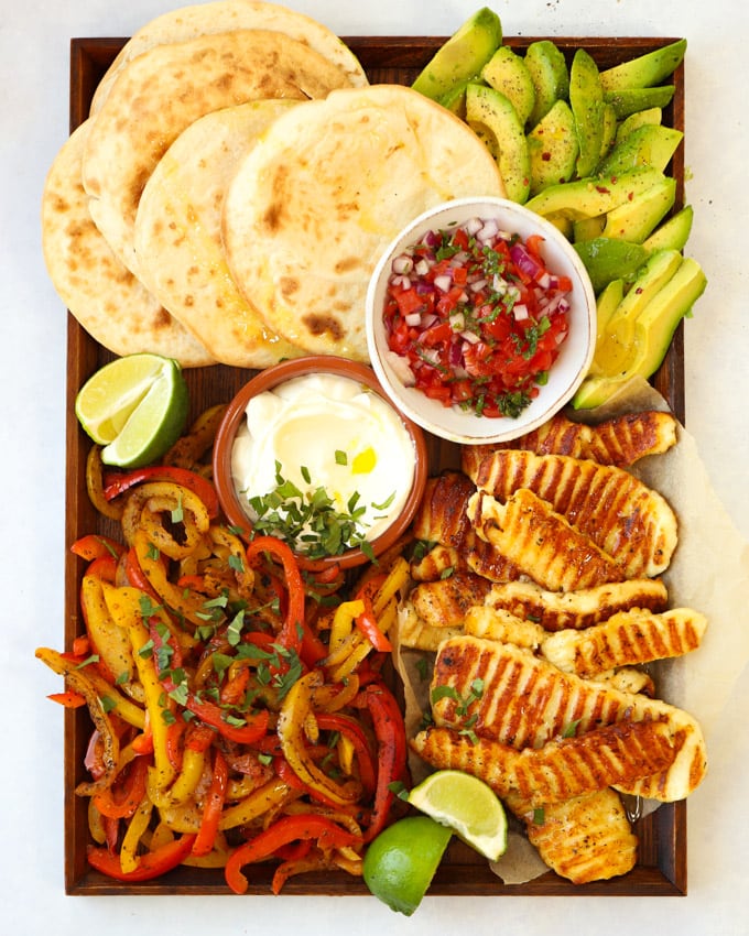 Halloumi fajitas recipe on a board with tortilla wraps avocado and salsa