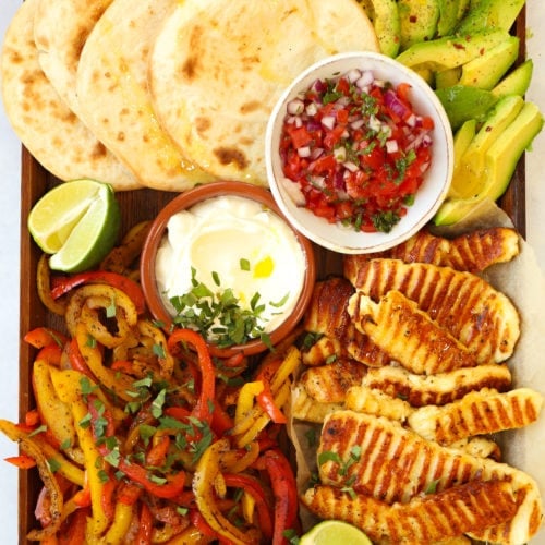 Halloumi fajitas recipe on a board with tortilla wraps avocado and salsa
