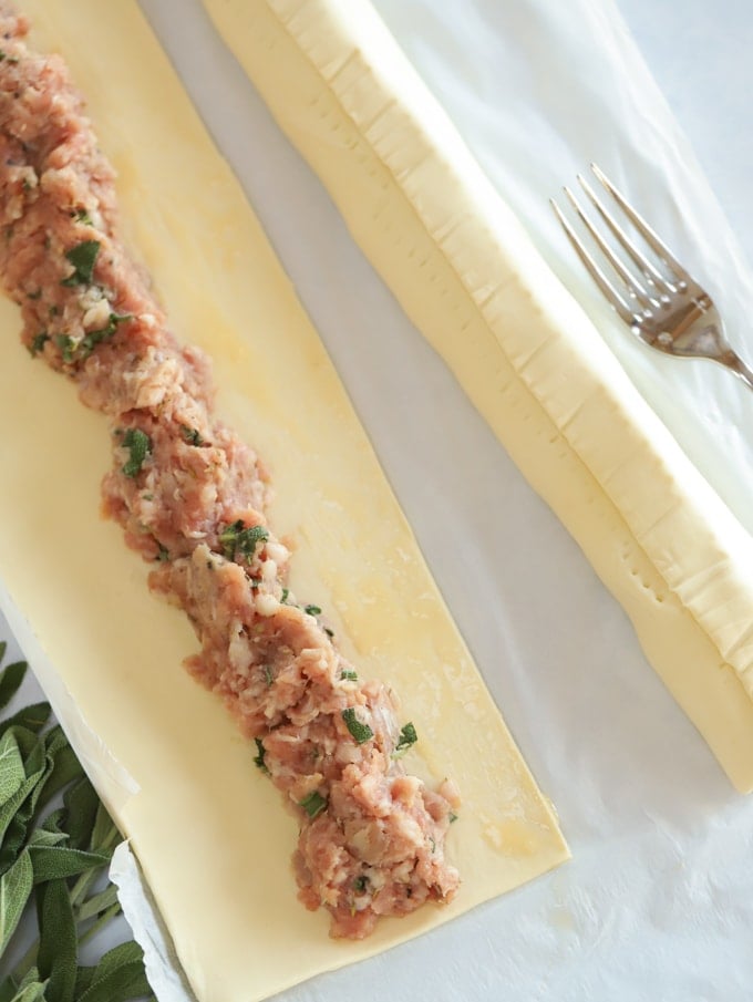 Roll of puff pastry with meat on top ready to be rolled