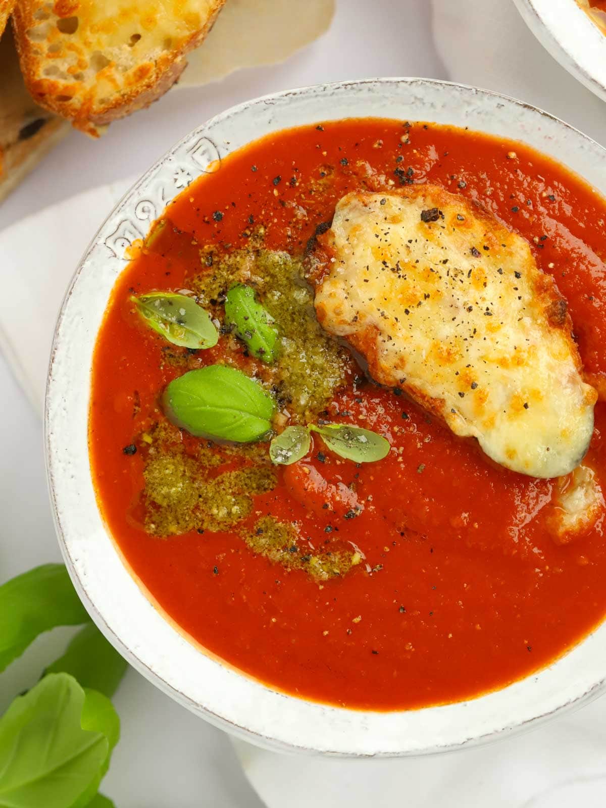 Delicious bowl of rich and easy Tomato Soup topped with pesto and cheesy toast.