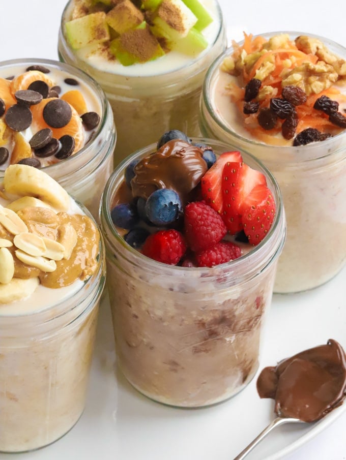 Jars of overnight oats recipe with carrots, strawberries, Nutella, berries and bananas.