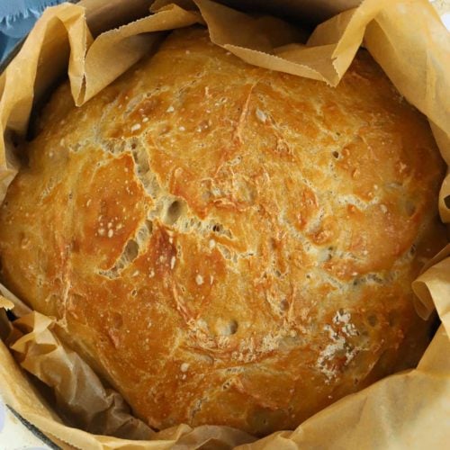 A golden homemade bread loaf in a pan, ready to serve.