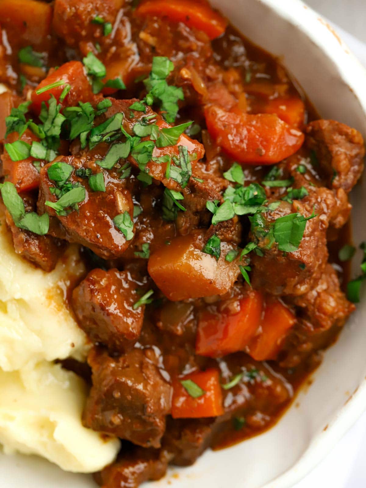 Meat casserole with carrots and gravy in a bowl with mashed potatoes