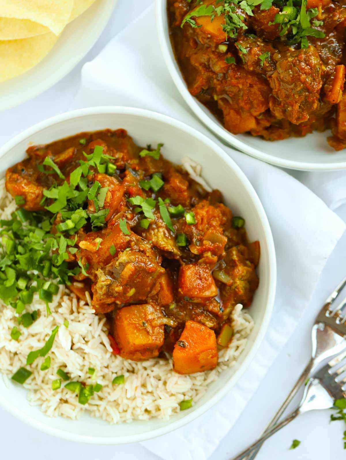 Two bowls filled with slow cooker lamb curry and rice.