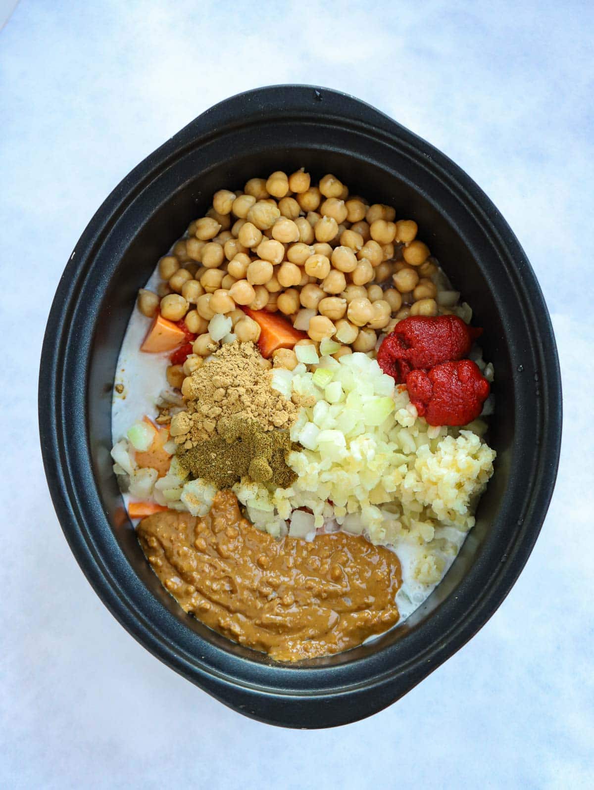 Uncooked ingredients for a sweet potato vegan stew in a slow cooker, ready to be cooked.