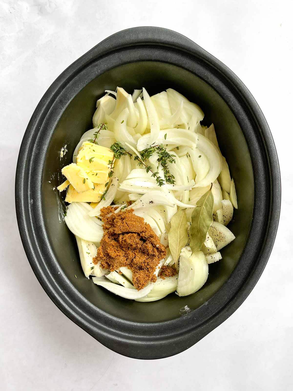 raw ingredients for french onion soup in slow cooker pan