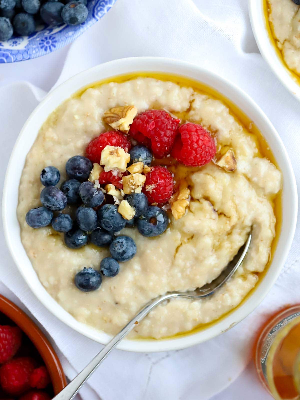 Bowl of slow cooker oatmeal topped with fruit and syrup.