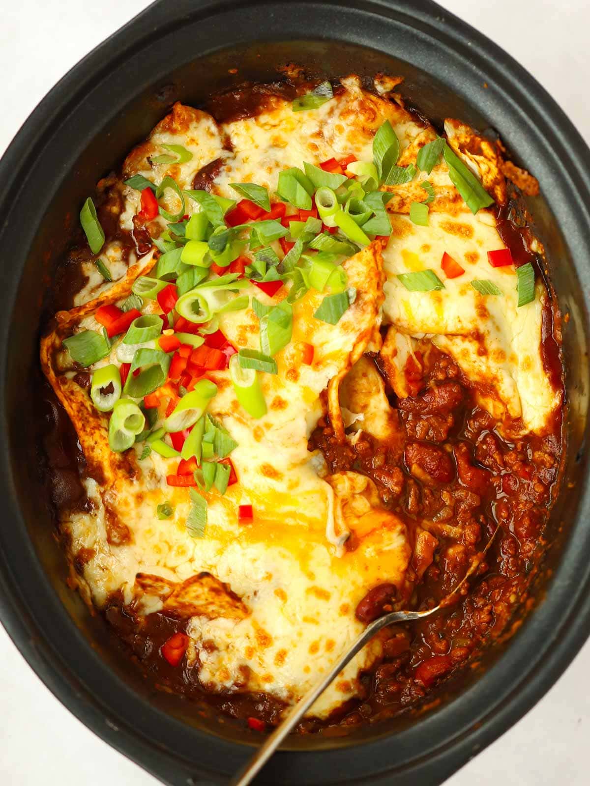 Beef mince enchiladas with cheese on top in a slow cooker, ready to be served.