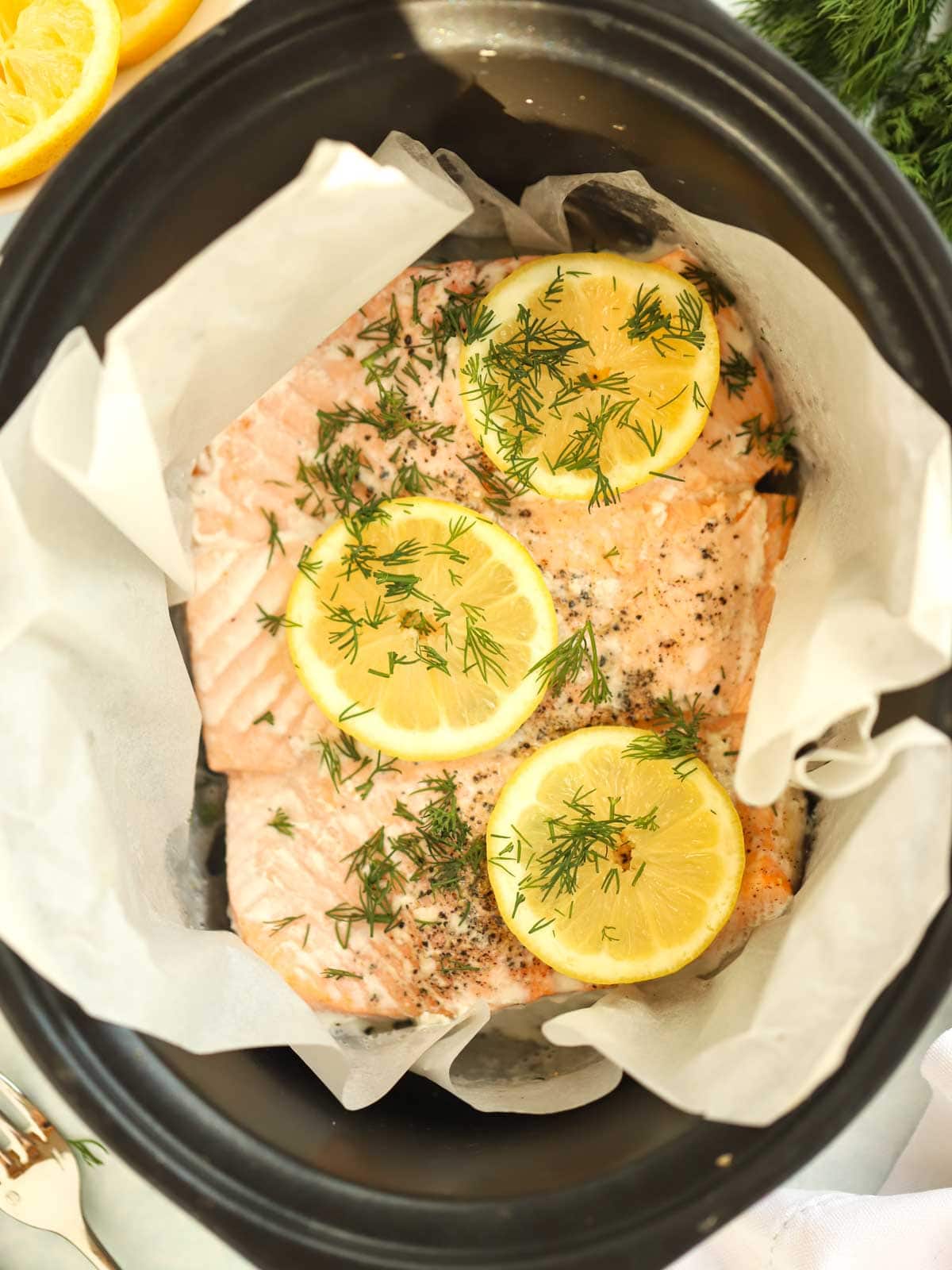 A side of salmon cooked in a slow cooker, wrapped in paper with lemon on top.