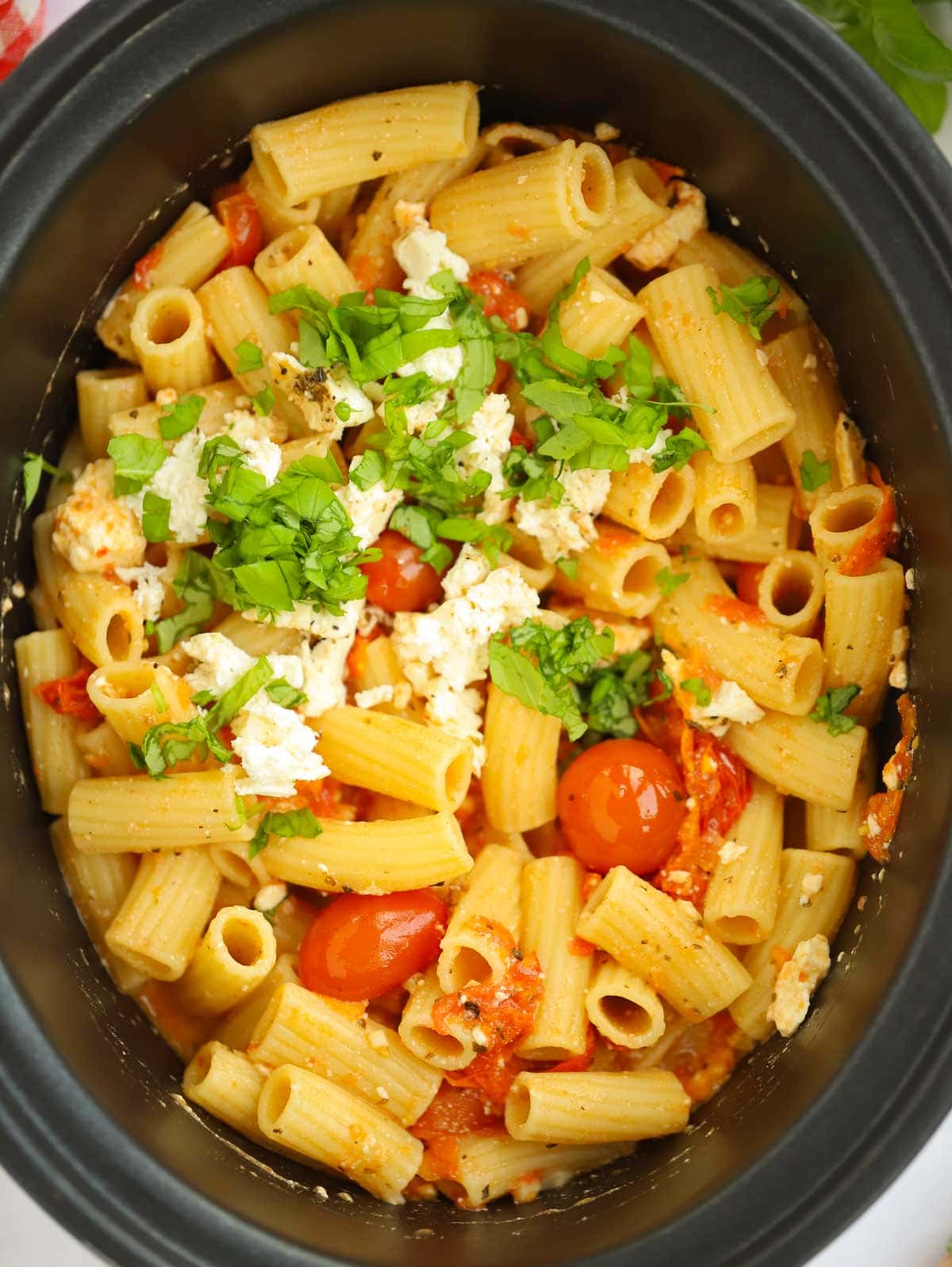 A slow cooker filled with cooked Feta and Tomato Pasta.