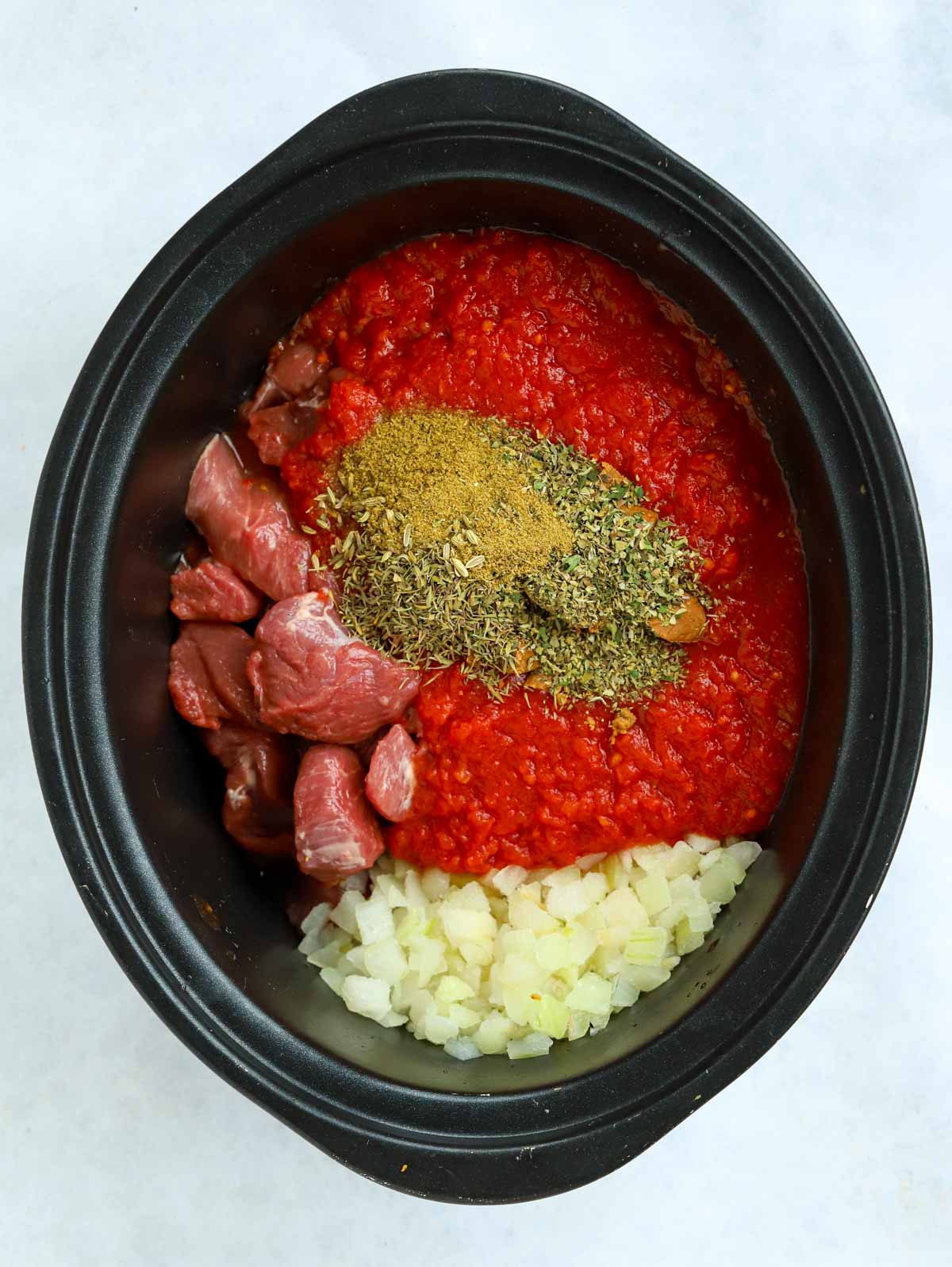 Raw ingredients in the slow cooker for Greek lamb casserole