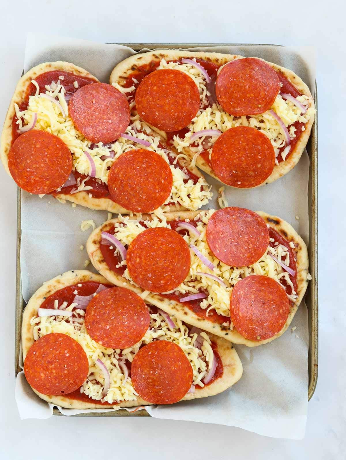 Easy naan bread pizzas topped with pepperoni before they go in the oven