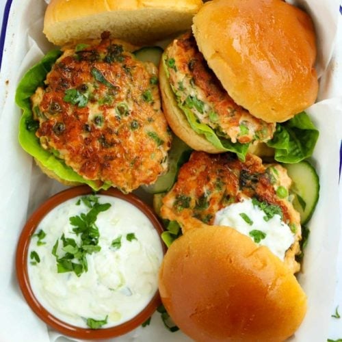 Delicious Salmon Burgers served on in a bap with salad and a side dressing of Tzatziki